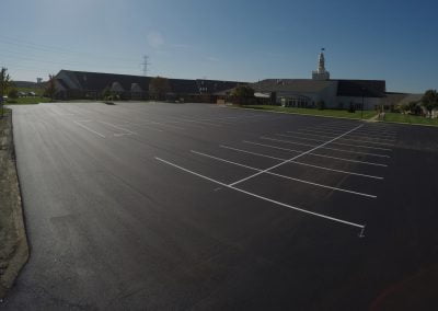 An empty, freshly paved and marked parking lot next to a large building shines under the clear blue sky in Charlotte, NC.