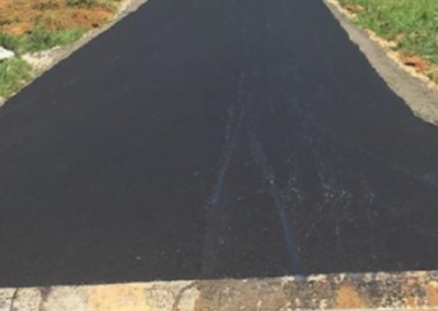A newly paved asphalt driveway, courtesy of top-tier asphalt paving in Charlotte, leads up to a house under construction, with greenery in the background.