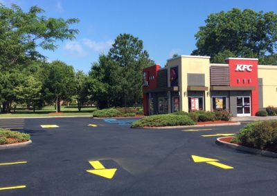 A KFC restaurant in Charlotte boasts an empty parking lot with pristine asphalt, set against a backdrop of clear blue sky.