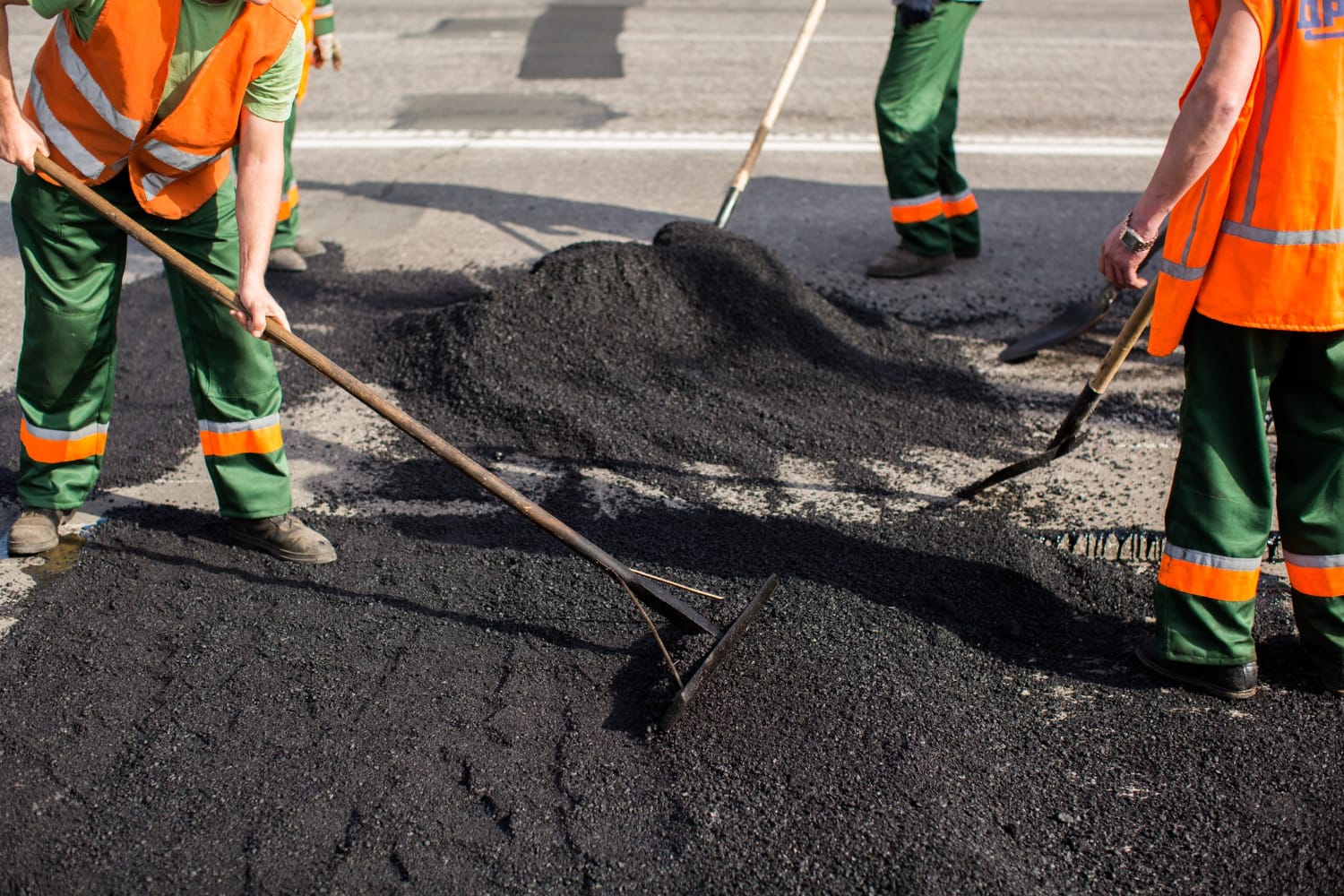 Asphalt Paving Work Asphalt Paving Work Workers in orange vests spreading asphalt on a road with shovels and rakes.